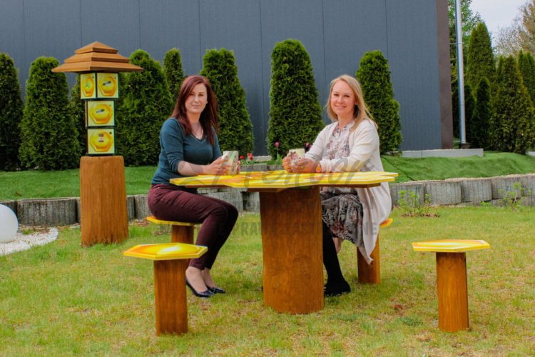 Pszczeli stolik z siedziskami - siedzą osoby dorosłe