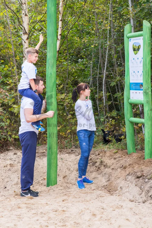 Tablica instalacyjna do urządzeń  - zdjęcie z realizacji. Dziewczyna odczytująca tablicę. Mężczyzna z dzieckiem na barana.